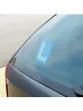 Blauw bordje met witte L voor lesvoertuigen